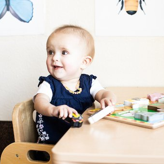 A baby is sitting at a table playing with toys.