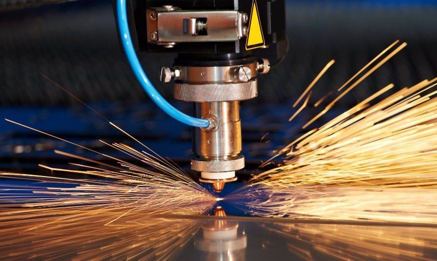 Eine Maschine schneidet ein Stück Metall, wobei Funken entstehen.