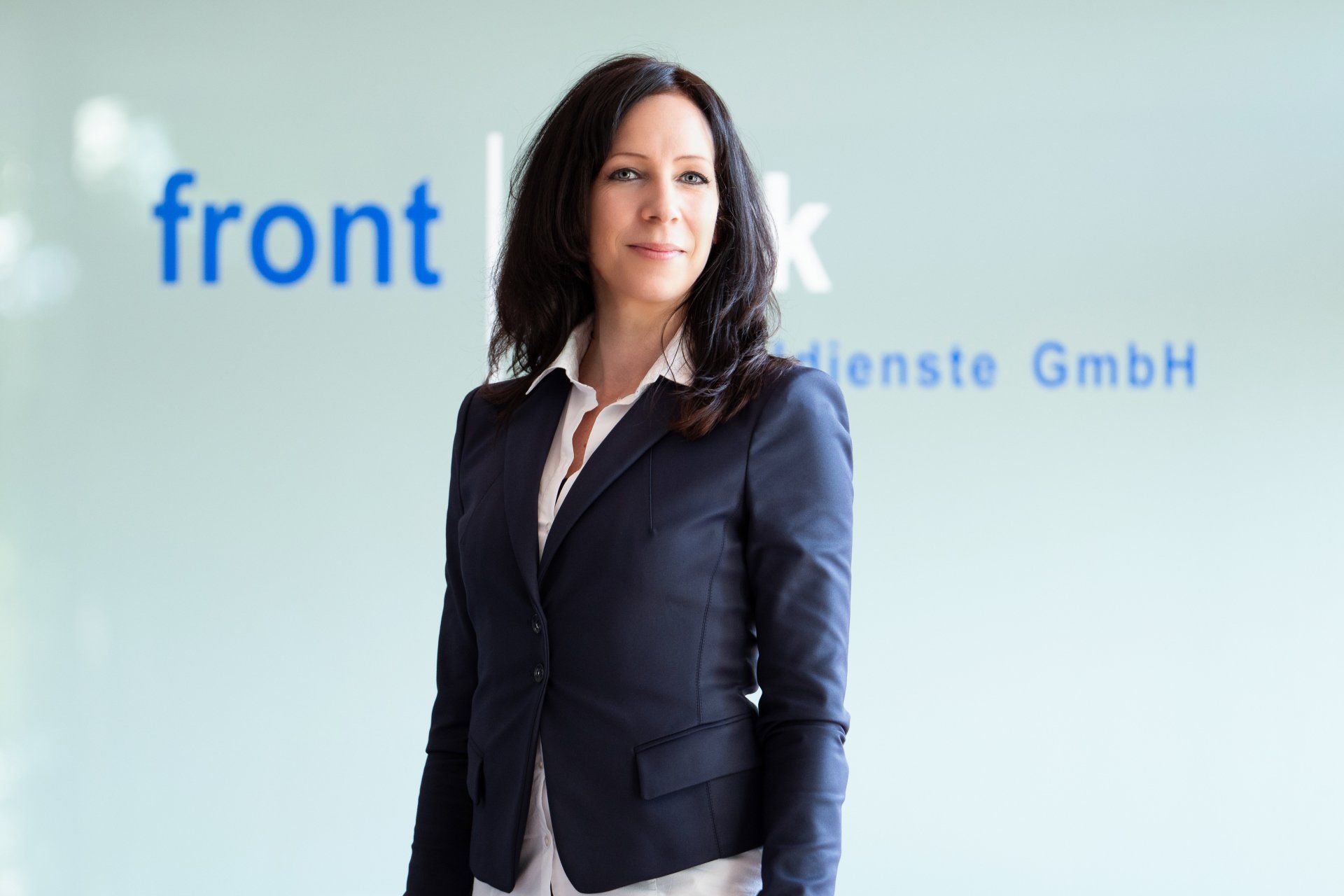 Eine Frau im Anzug steht vor einem Schild mit der Aufschrift „Front“