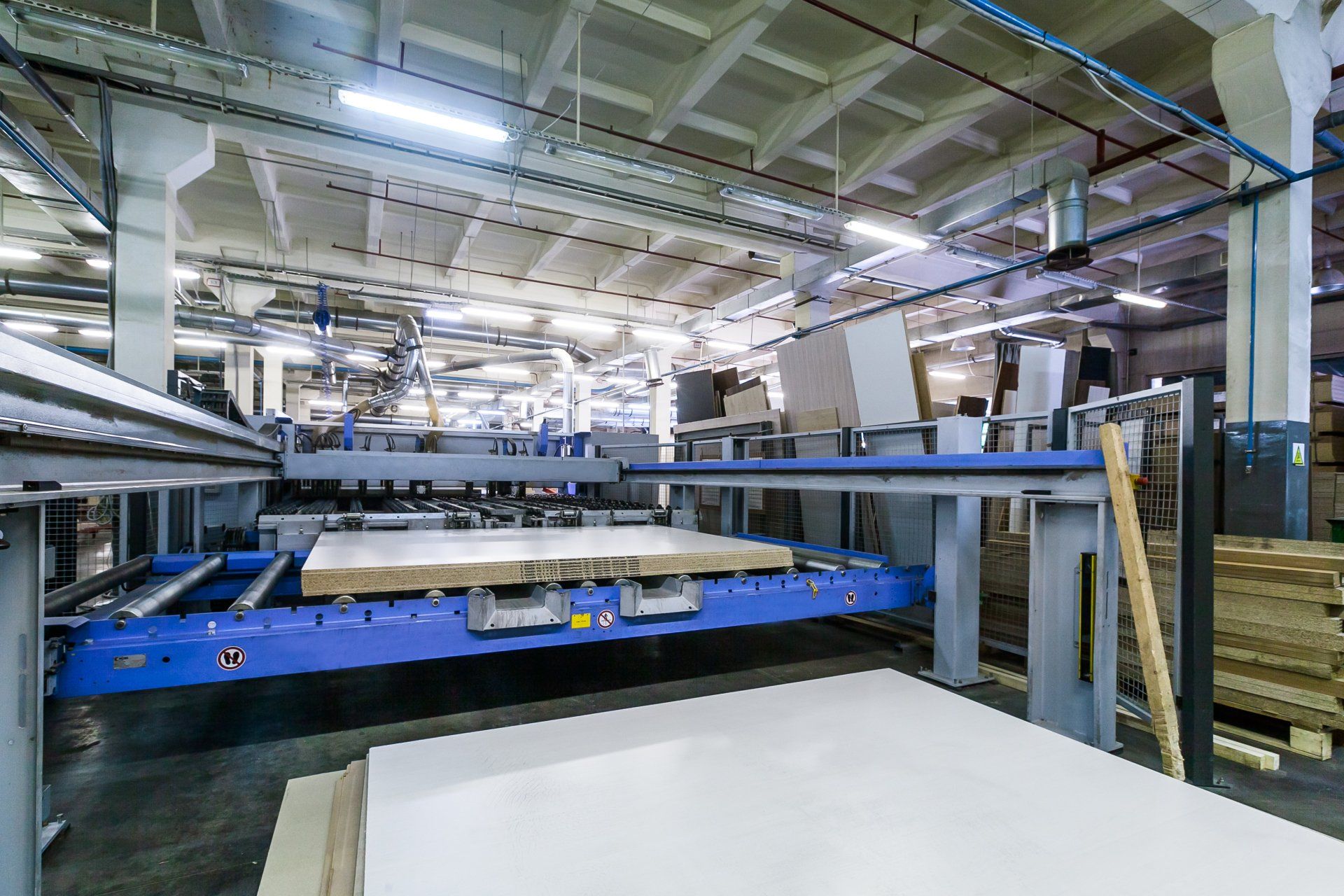 In einer Fabrik schneidet eine Maschine ein Stück Holz.