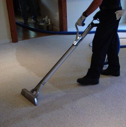 Man Cleaning the Rug - Cleaning Services in Lothian, MD Person using a carpet cleaner on beige carpet in a hallway