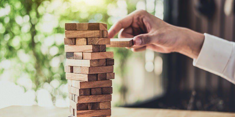 Hand placing a wooden block on a Jenga tower