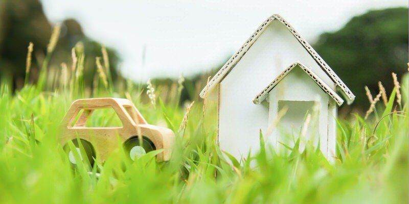 Toy car beside a small white house in tall green grass