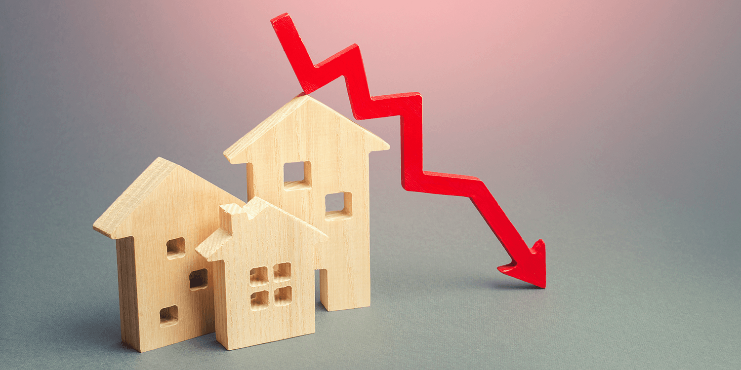 Small wooden houses with a red downward zigzag arrow, suggesting a drop in home values