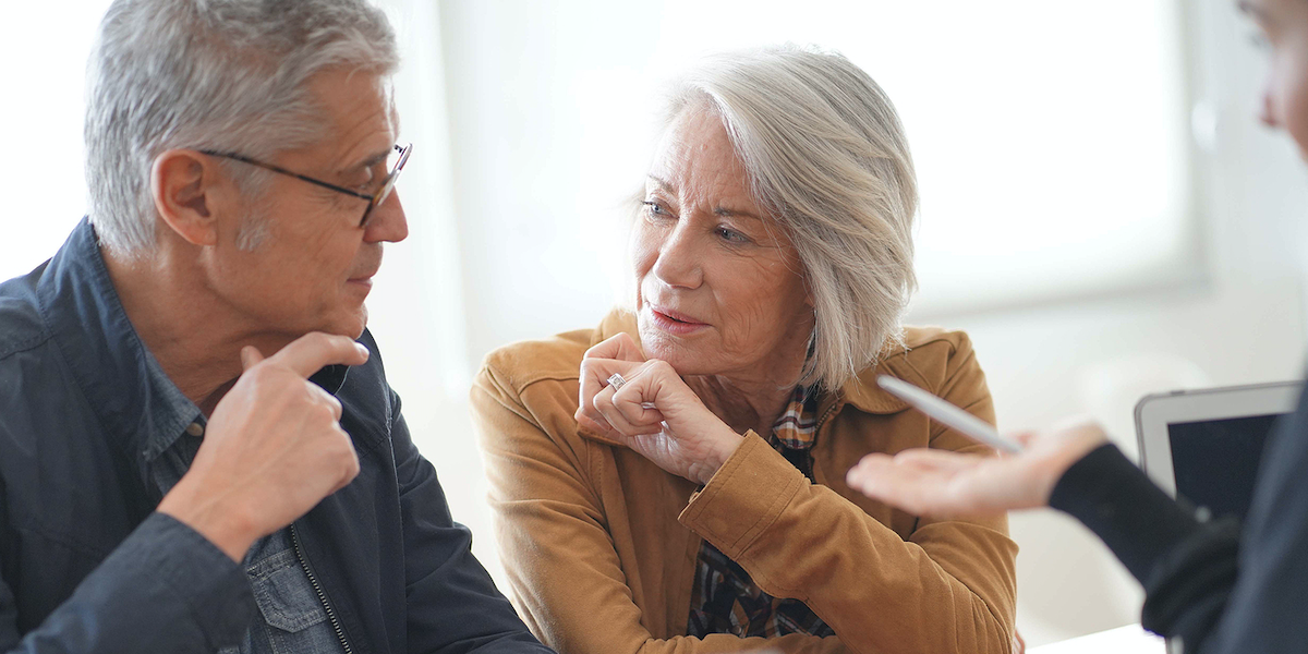 Two people talking at a table, with one gesturing while the other listens attentively