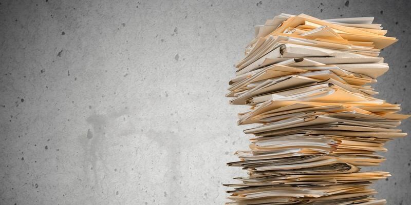 Stack of papers on a gray surface, piled high on the right side