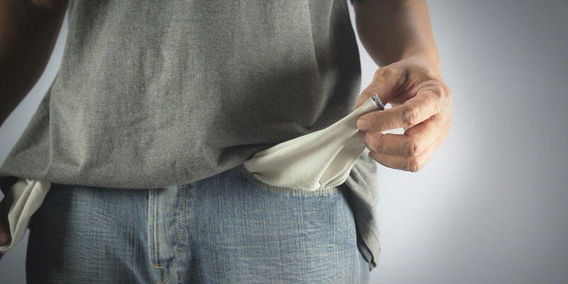 Person pulling an empty pocket inside blue jeans, showing no money