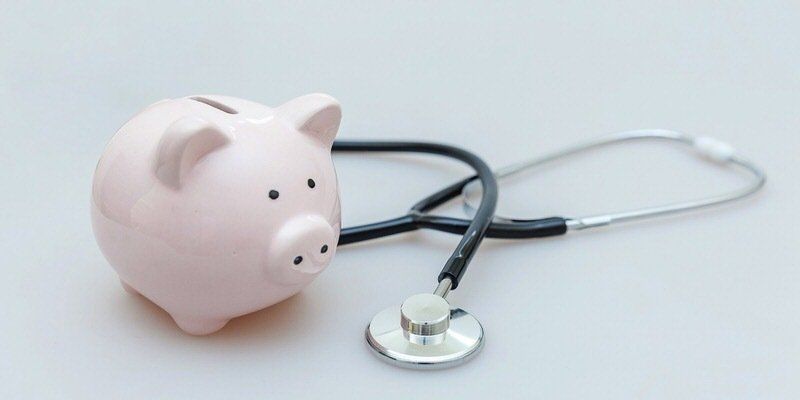 Pink piggy bank with a stethoscope on a white background