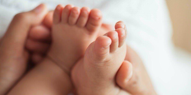 Close-up of tiny baby feet being gently held in adult hands
