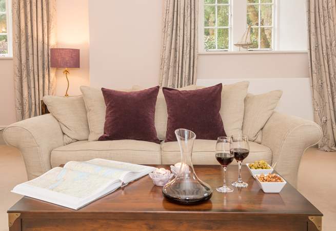 Living room with beige sofa, maroon pillows, coffee table with wine and snacks.