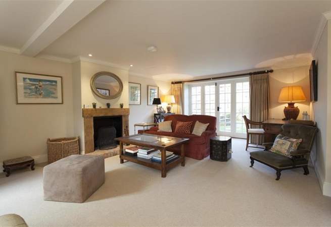 Living room with fireplace, red couch, desk, and French doors leading to a patio.