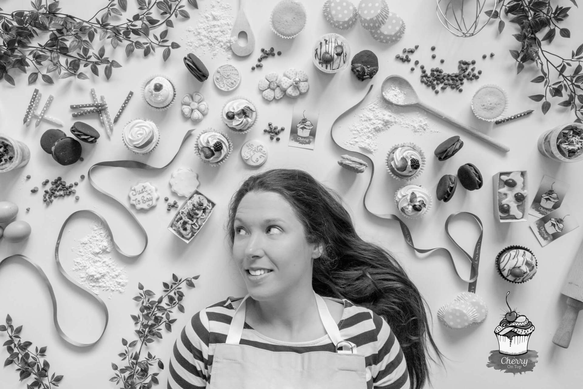 Woman in striped shirt looks up, surrounded by baking items and pastries.
