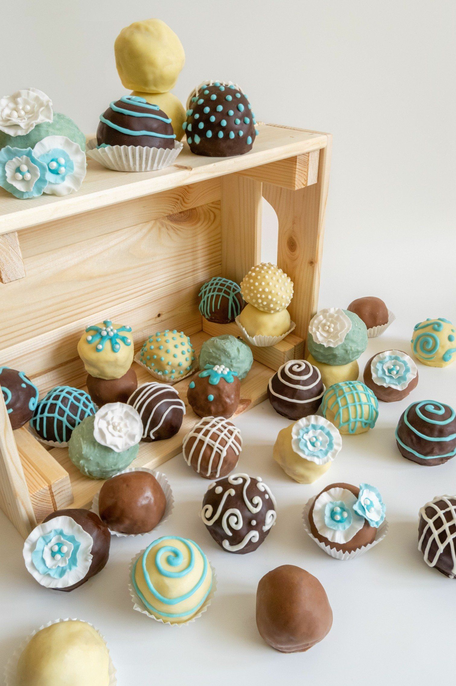 Cake pops in various colors and designs, spilling from a wooden crate.