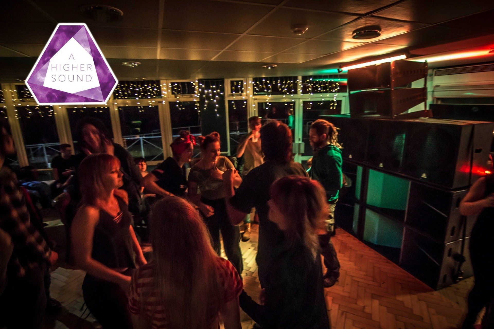 People dancing in a dimly lit club. Purple logo
