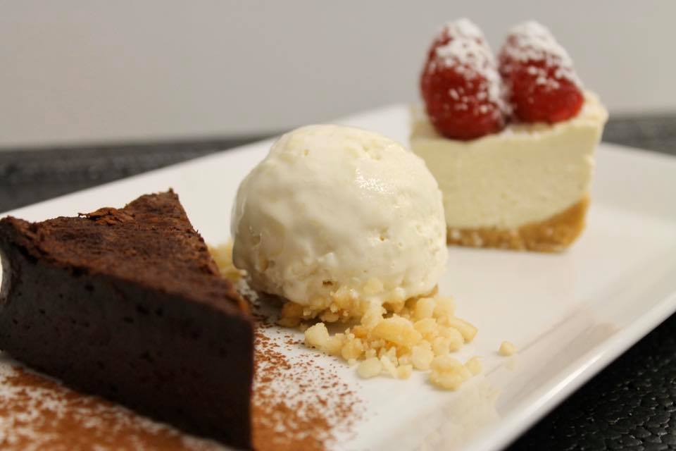 Dessert plate with chocolate cake, vanilla ice cream, and cheesecake topped with berries.