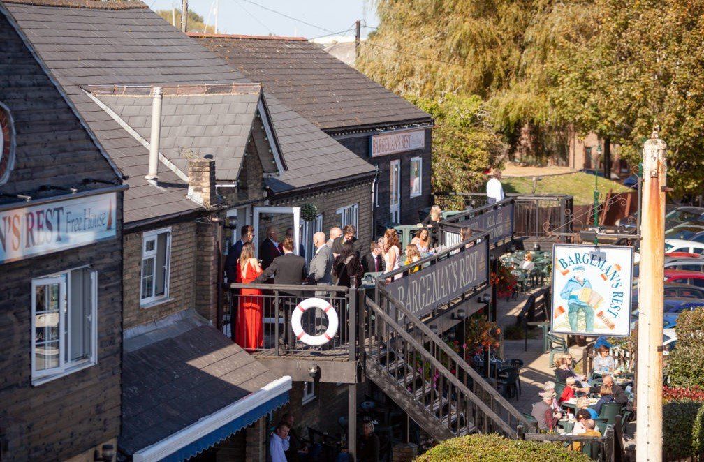 Restaurant with outdoor deck, people gathered. Wooden building, signage.