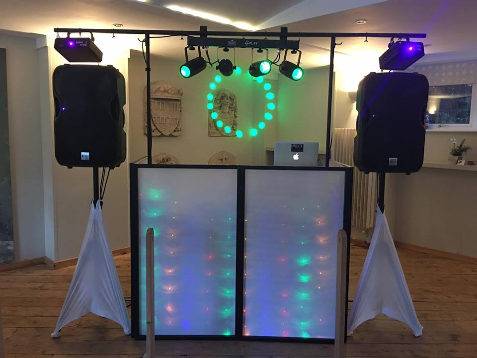 DJ setup with speakers, lights, and a glowing centerpiece on a stage.