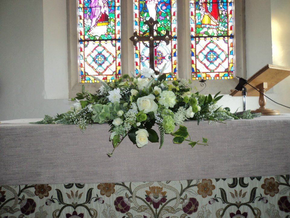 Flower arrangement on altar in front of stained glass windows.