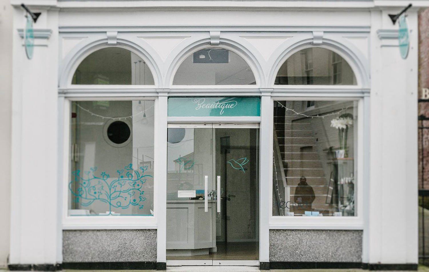 White storefront with arched windows and glass doors,