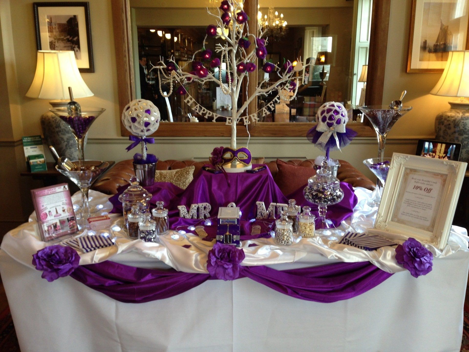 Wedding dessert table with purple and white decorations.