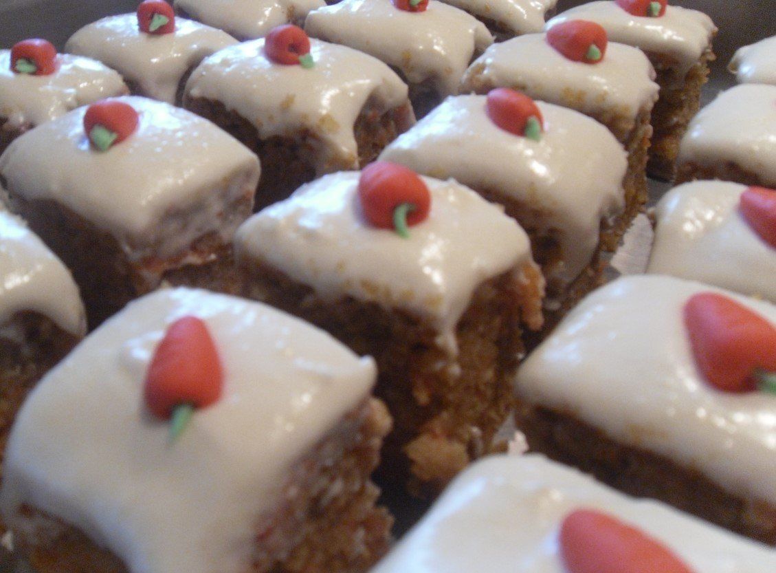 Frosted carrot cake squares topped with small red marzipan carrots.