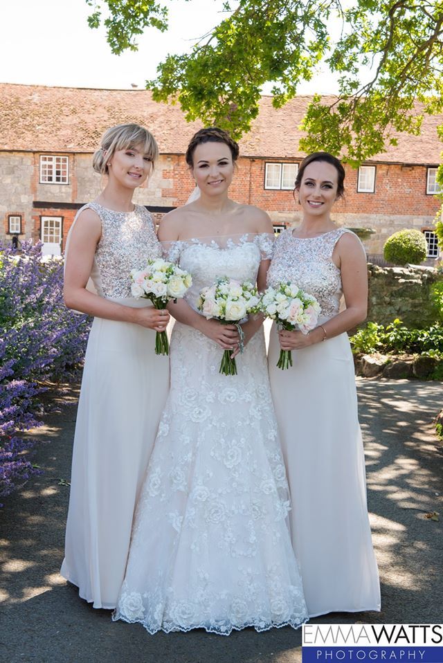 Bride and bridesmaids pose outside a building, all holding bouquets.