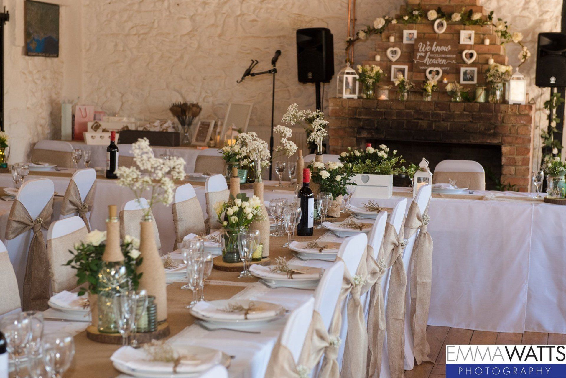 Wedding reception table setting with floral arrangements, wine, and decorative details.