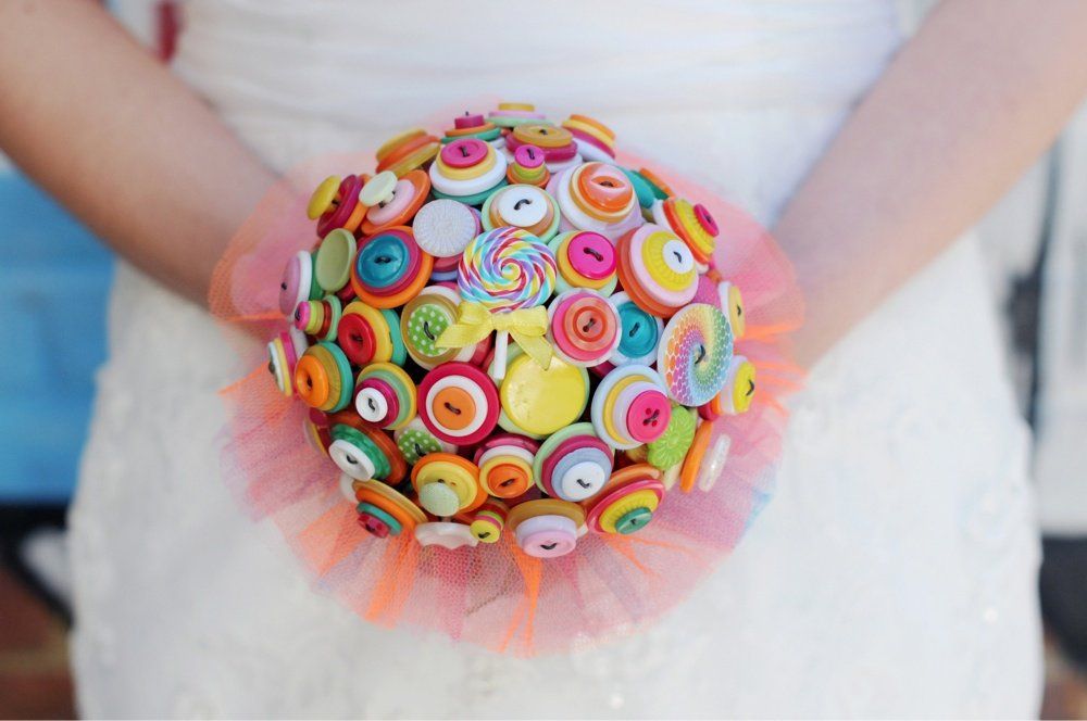 Bride holding a colorful button bouquet with tulle accents.