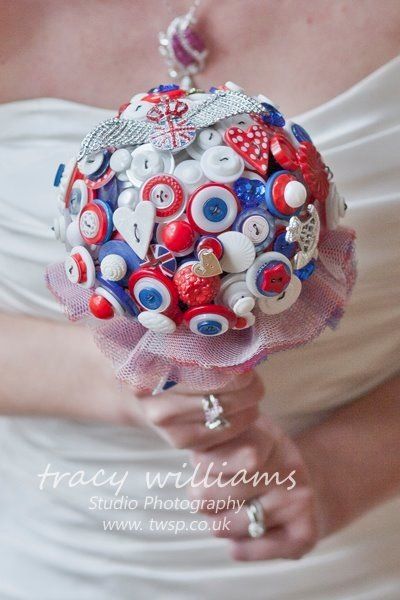 Bride holding a button bouquet, red, white, and blue, with a tulle wrap.