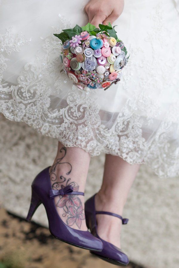 Bride holding a button bouquet, wearing purple heels, and with ankle tattoo.