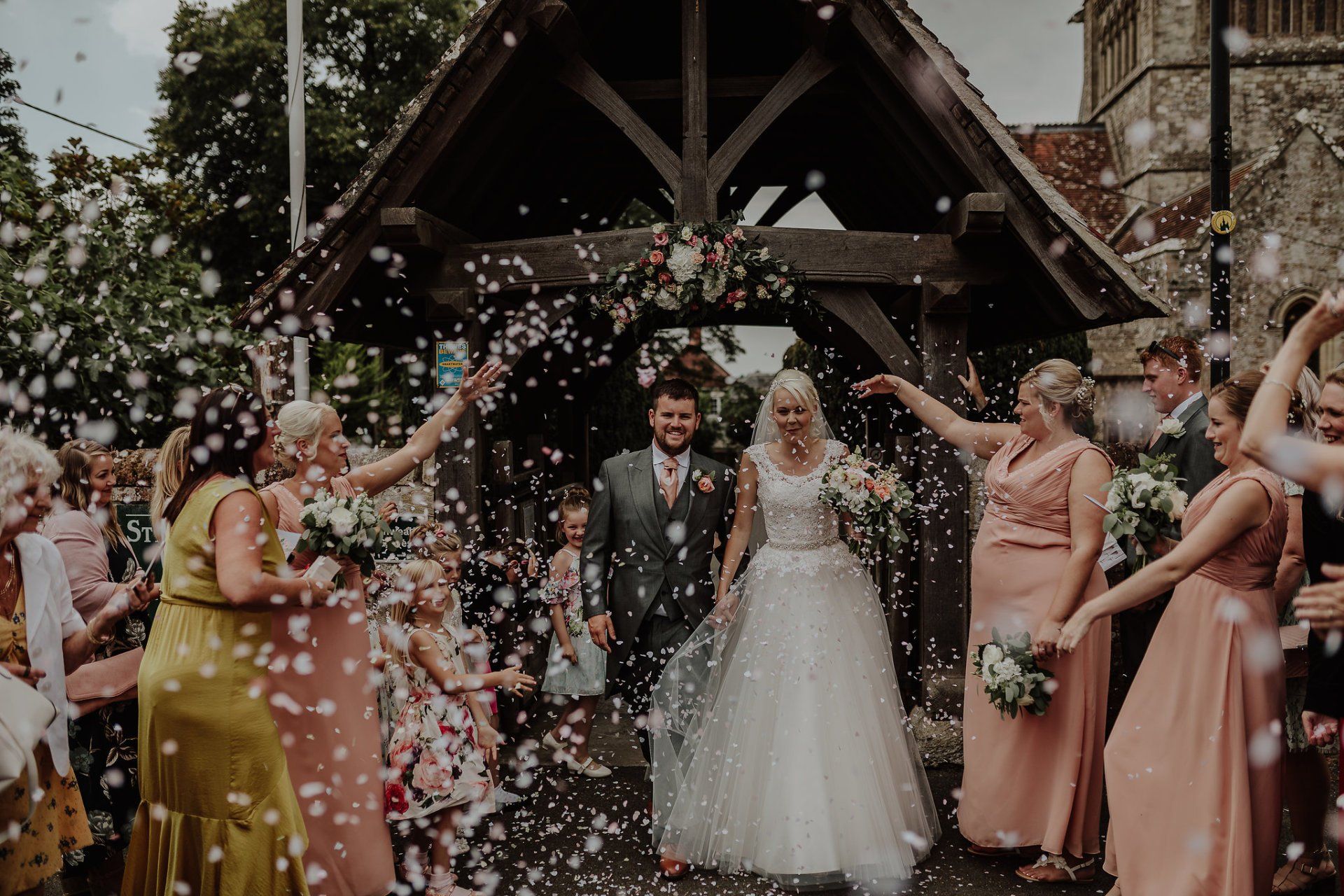Bride and groom exit church as guests throw confetti.