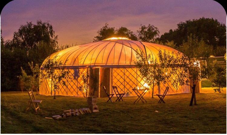 Illuminated yurt at dusk with outdoor seating.