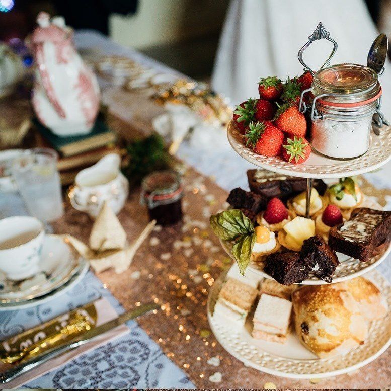 Tiered dessert tray with strawberries, pastries, and sugar. Tea setting with decorative paper crane.