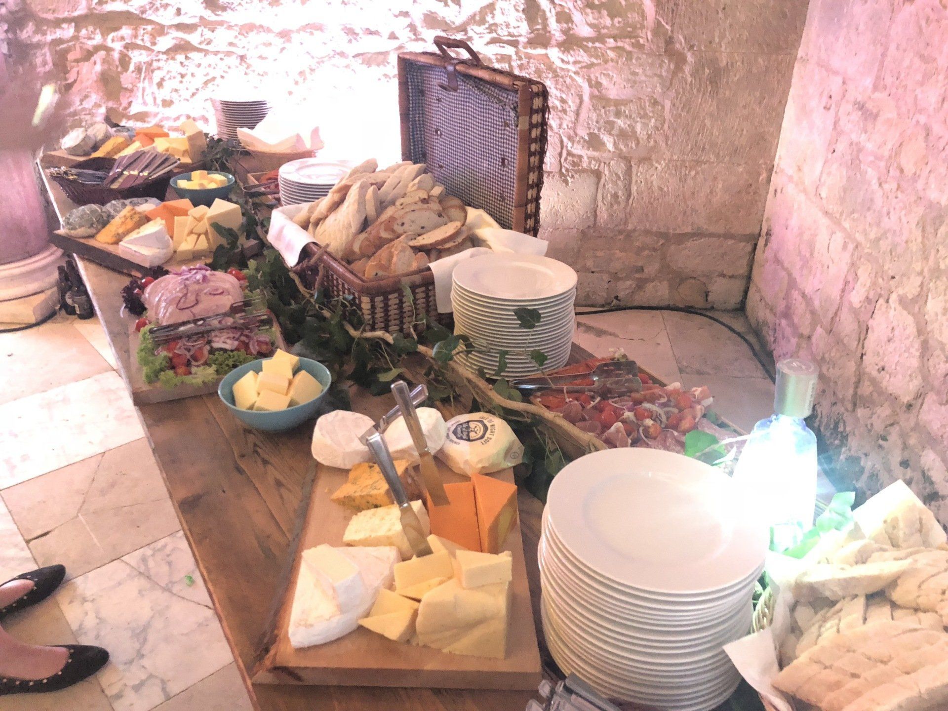 Cheese and bread buffet on a wooden table set against a stone wall.