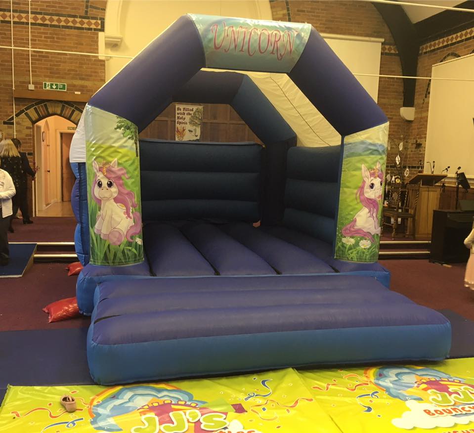 Blue unicorn bouncy castle inside a hall, decorated with pink unicorns.