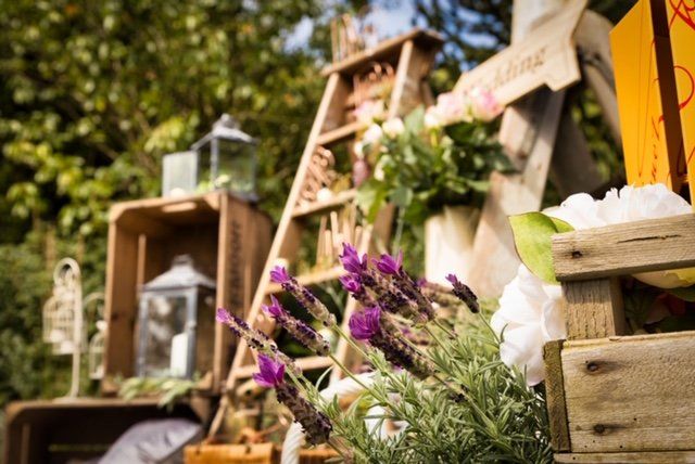 Rustic wedding decor with wooden crates, ladder, lavender, lanterns, and sign.