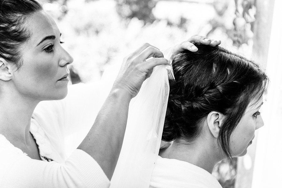 Woman styling another woman's hair, preparing for an event. Black and white photo.