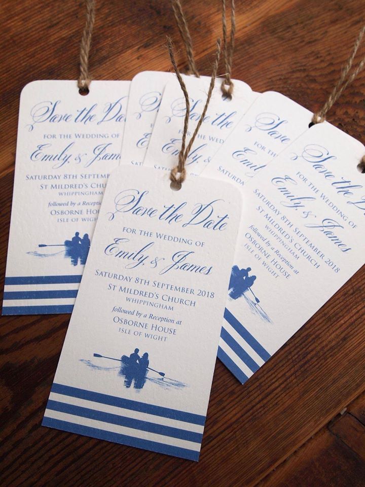 Save the date tags with blue text and a rowing boat design, hanging from twine, on a wooden surface.
