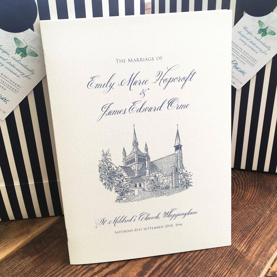 Wedding program: Cream card with navy script and church illustration.