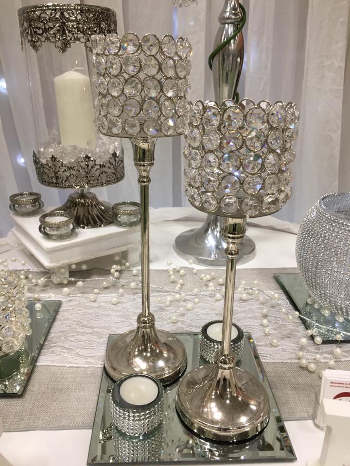 Silver candle holders with crystal accents, on a table with pearls.