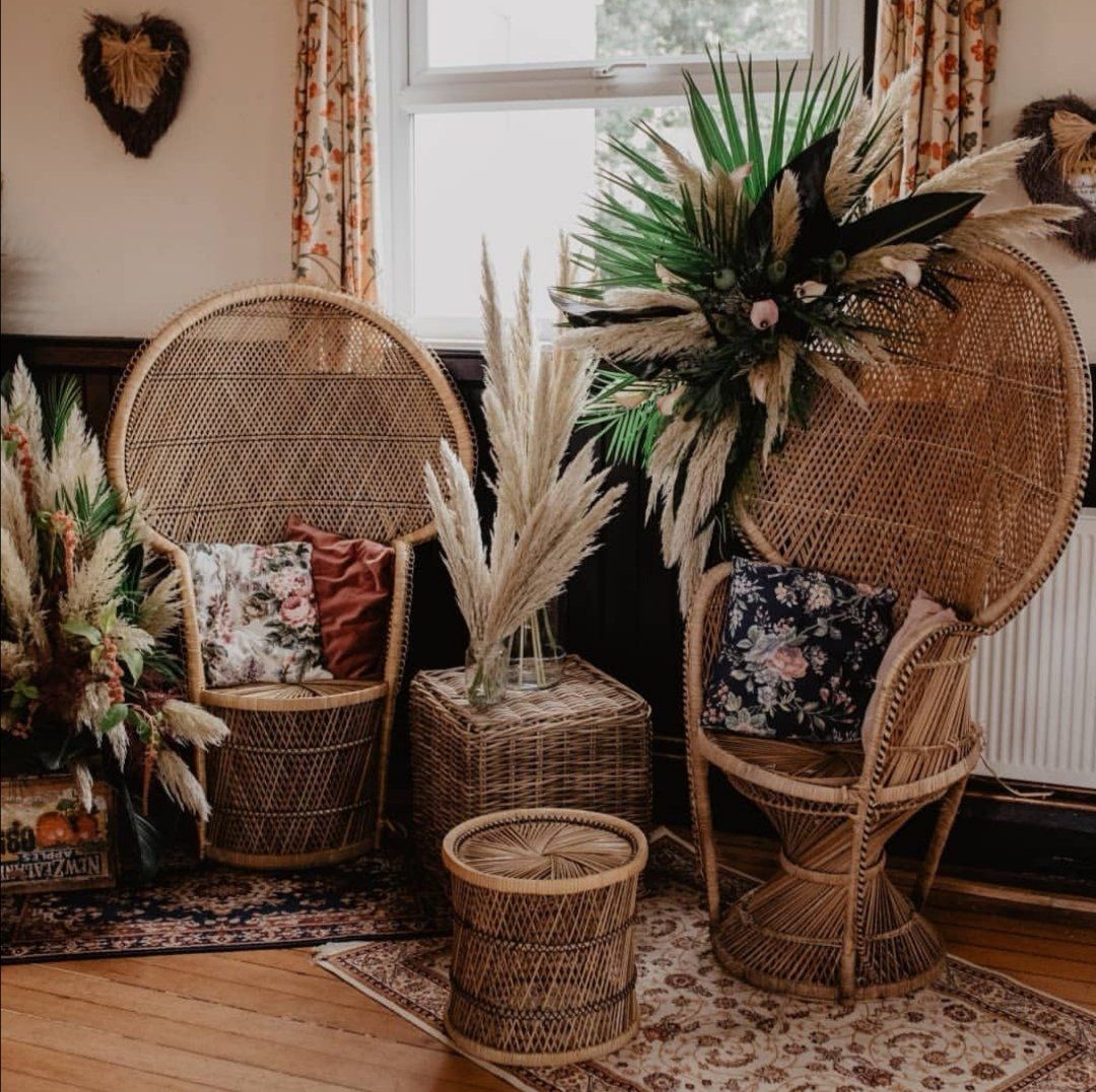 Boho chic interior with peacock chairs, pampas grass, floral pillows, and wicker accents.