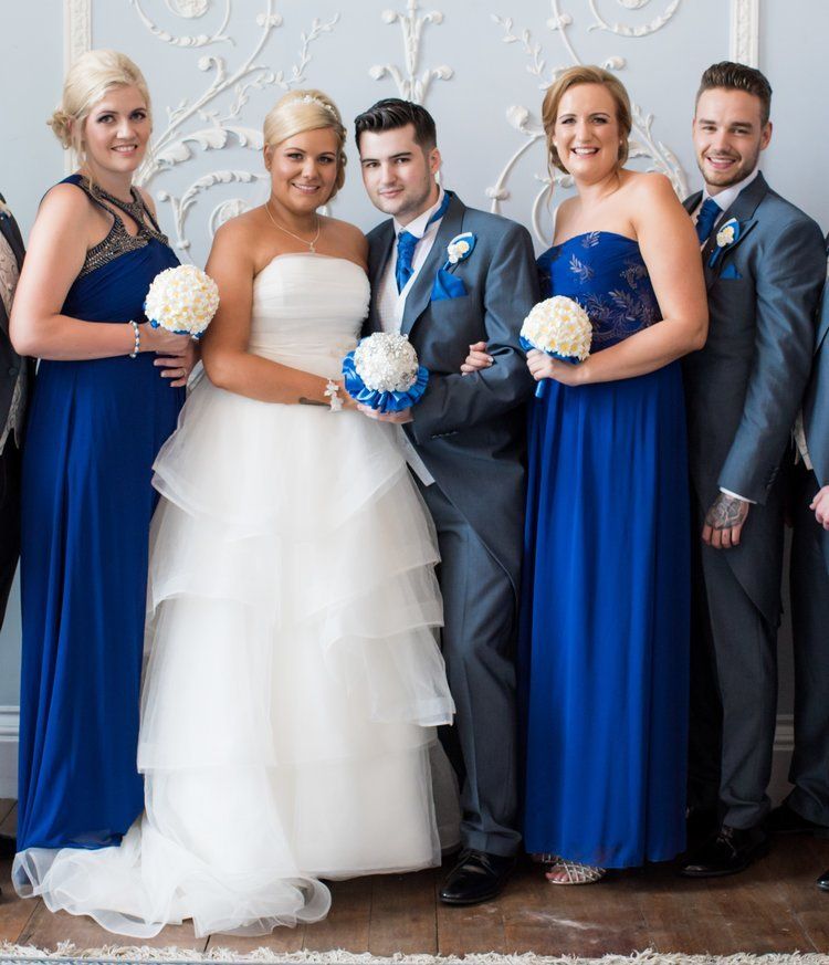 Wedding party: Bride in white dress, groom in gray suit, bridesmaids in blue dresses, holding bouquets.