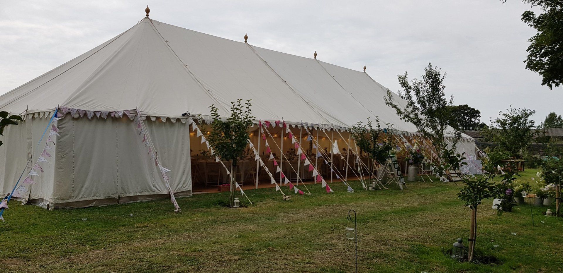 A large white tent set up on a grassy lawn, likely for an outdoor event.