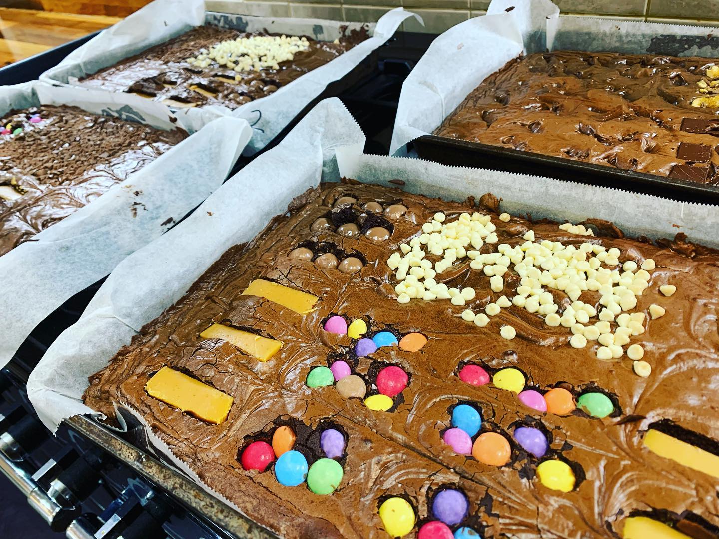 Brownies in baking pans, topped with candies and chocolate chips.