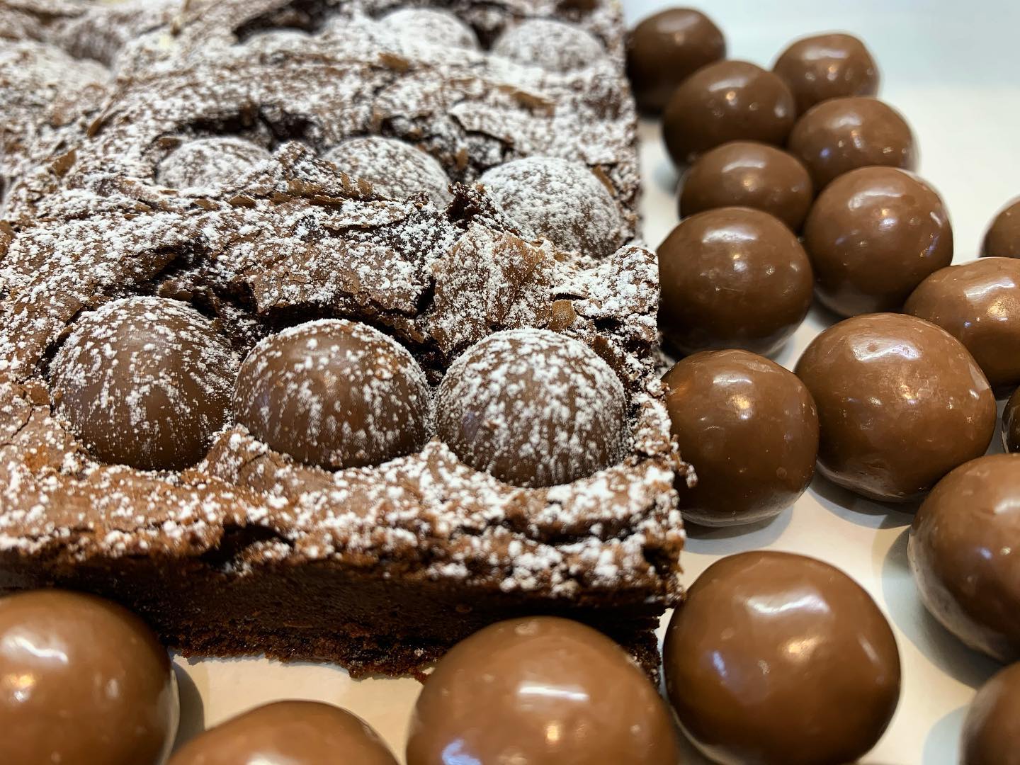 Chocolate brownie with Maltesers, dusted with powdered sugar.
