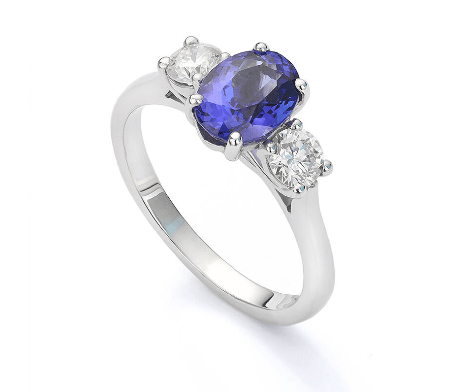 Silver ring with a large oval blue gemstone and two smaller white diamonds.