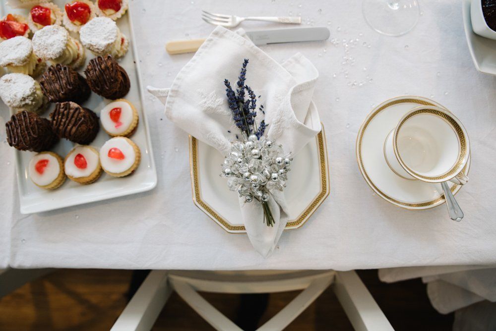 Table set for tea with pastries, a napkin with flowers, and a teacup.
