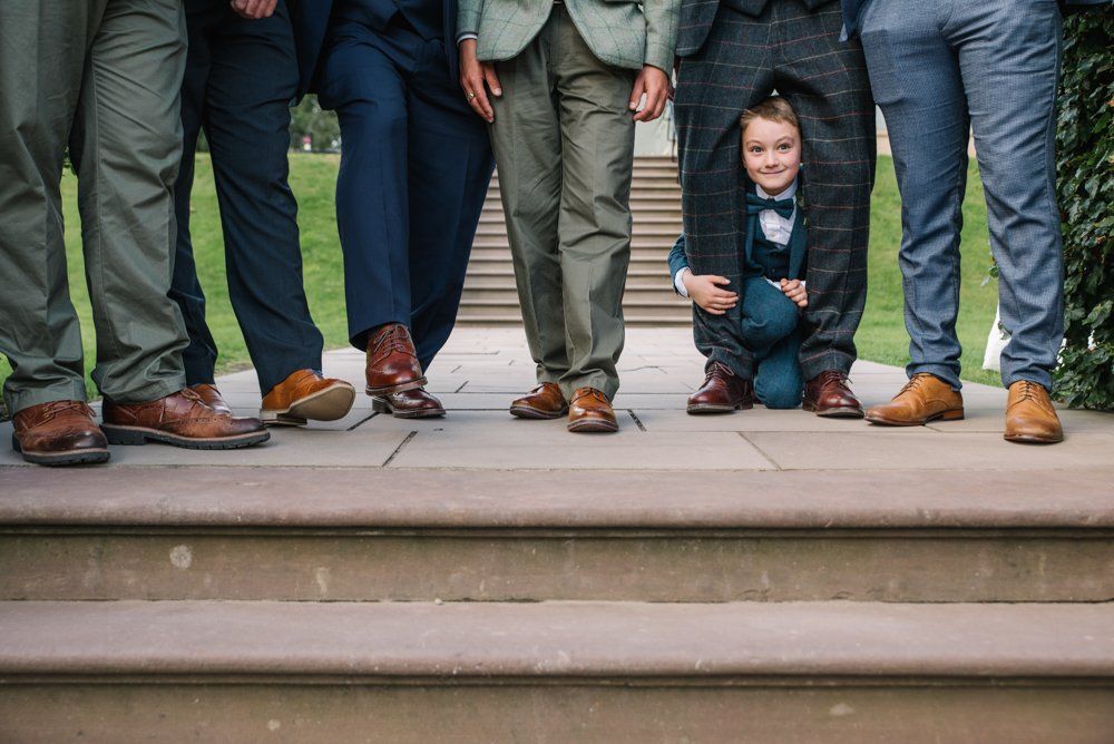 Group of men in suits stand on steps, with a child hiding between their legs.