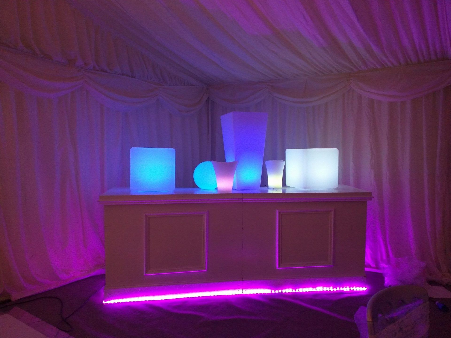 Bar with glowing colorful lights inside a tent.