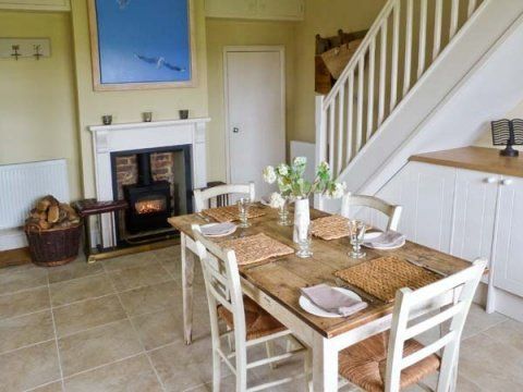 Dining room with table set for four, fireplace, and stairs.